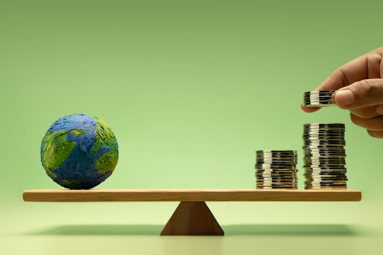 Scales balancing a dollar sign on one side and the planet on the other.