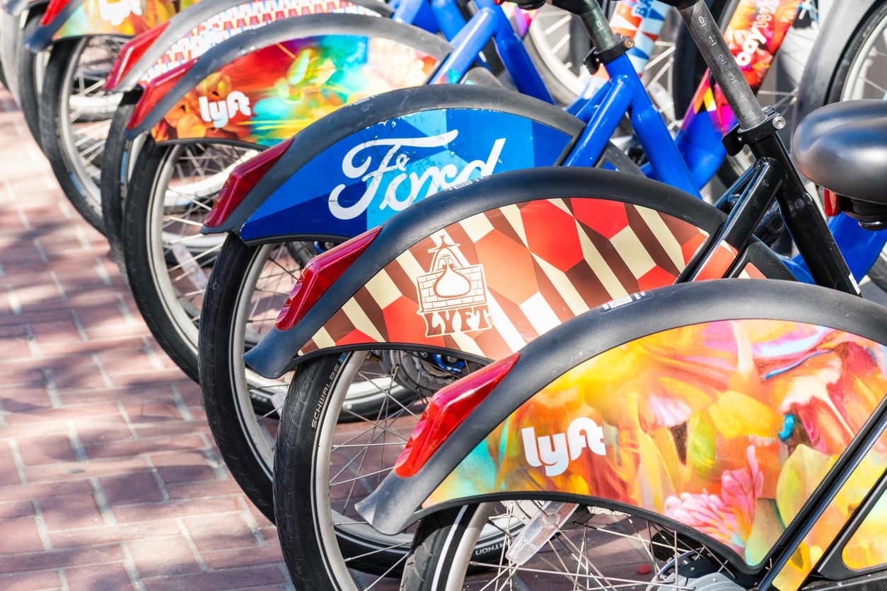 A row of e-bikes available for rent on a university campus.