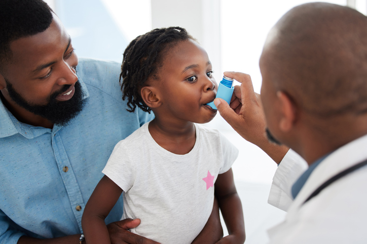 A young child using an asthma inhaler.