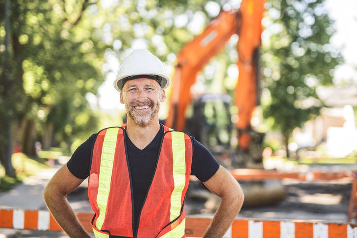 A construction worker wearing a hard hat and safety vest outdoors.