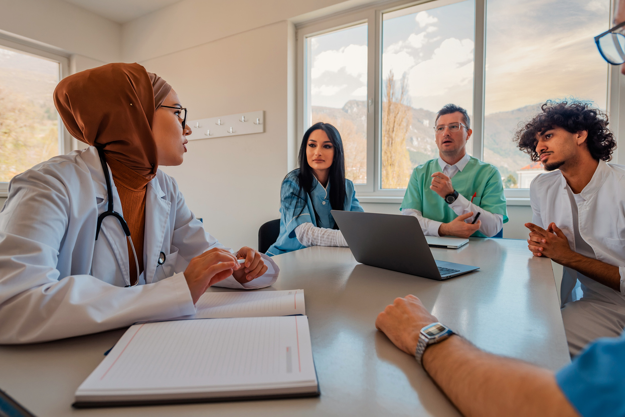 A diverse group of medical professionals sitting around a table in a meeting.