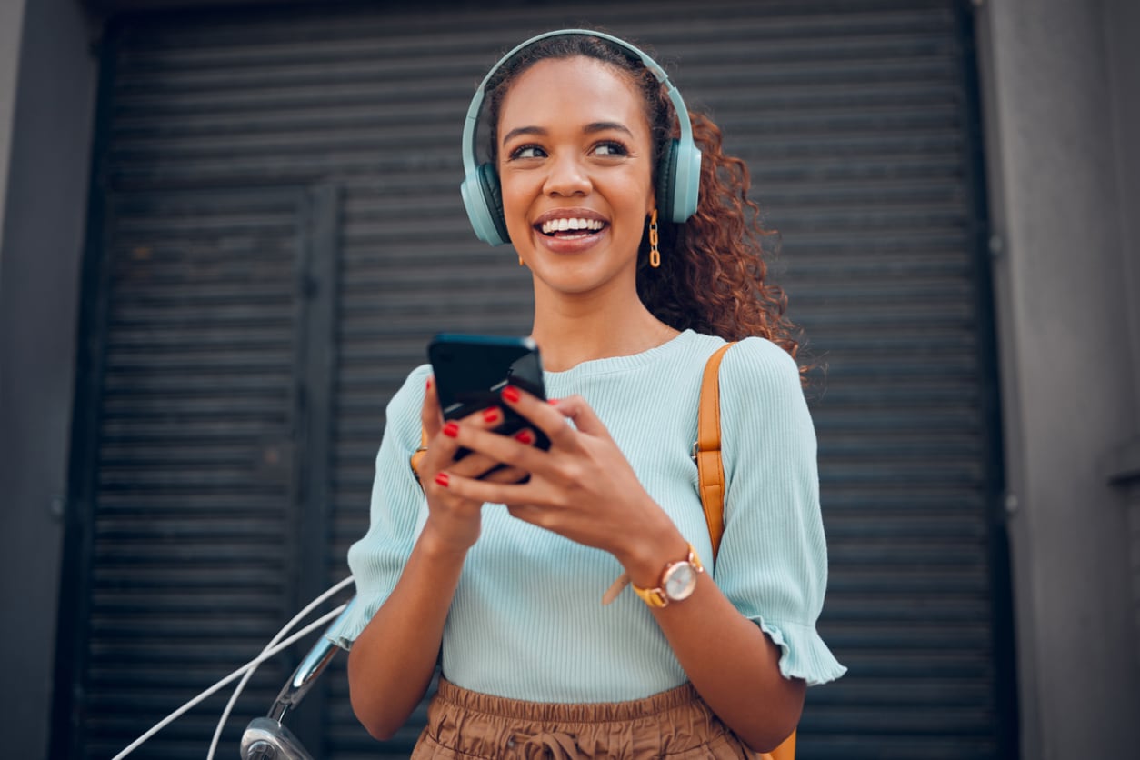A young person smiling while listening to music with large headphones.