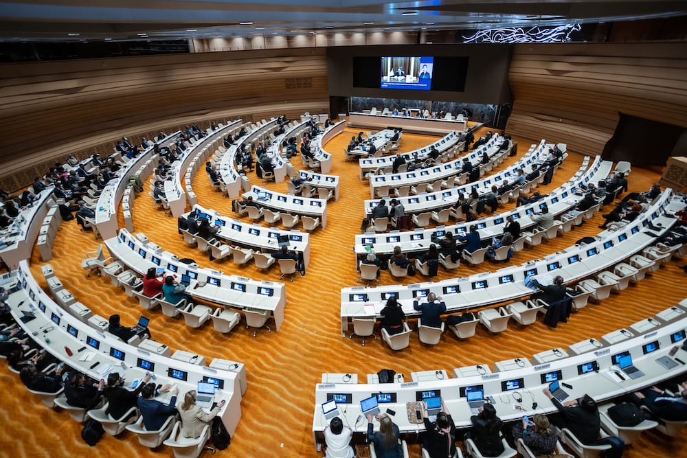 A formal meeting in a large hall with delegates from many countries.