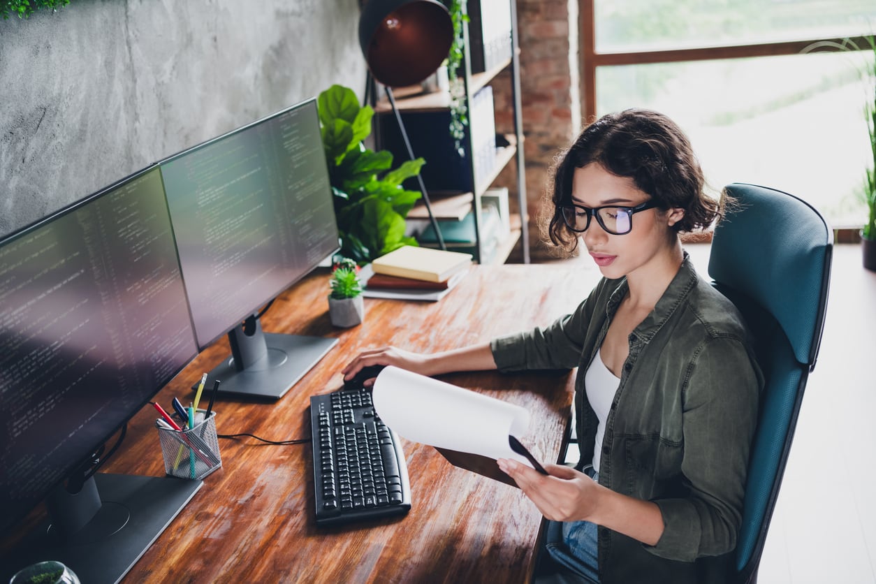 A programmer working on code on multiple computer screens.